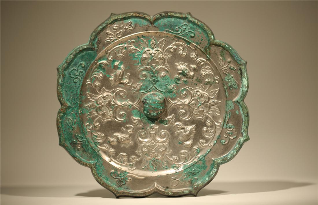 A BRONZE MIRROR.TANG DYNASTY: Heavily cast and of linghua (water chestnut flower) shape, finely and crisply cast with lotus stems flanking the knob, above the knob is another lotus stem, its leaves supporting a pair of pendent flo