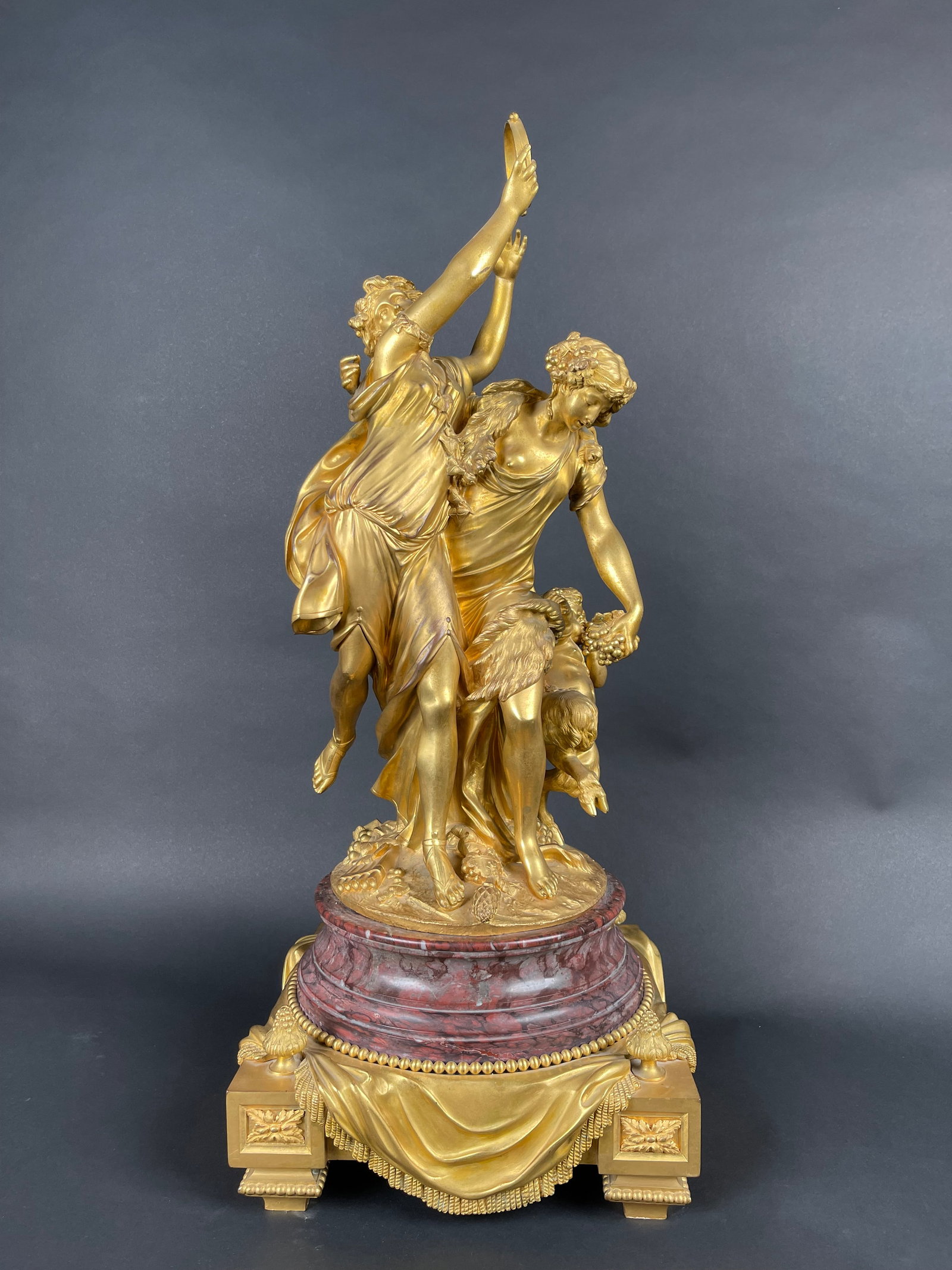 A FRENCH ORMOLU GROUP OF TWO BACCHANTES AND A SATYR: A FRENCH ORMOLU GROUP OF TWO BACCHANTES AND A SATYR MOUNTED ON A ROUGE MARBLE BASE . AFTER A MODEL BY CLODION, LATE 19TH OR EARLY H: 31" W: 12-1/2" D: 12-1/2"