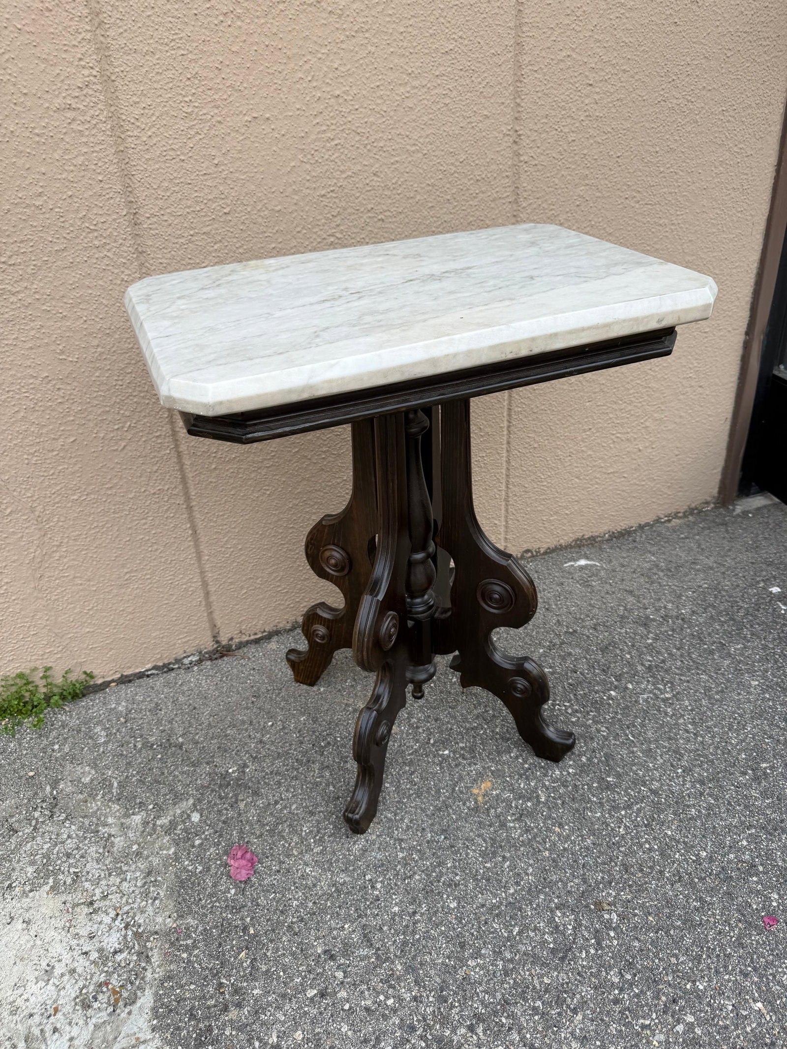 Antique Marble Top Pedestal Side Table: Elegant side table has a rectangular white marble top with grey veining and beveled edges. The dark brown wooden base is constructed with a central turned pedestal and four ornate, scroll-carved legs