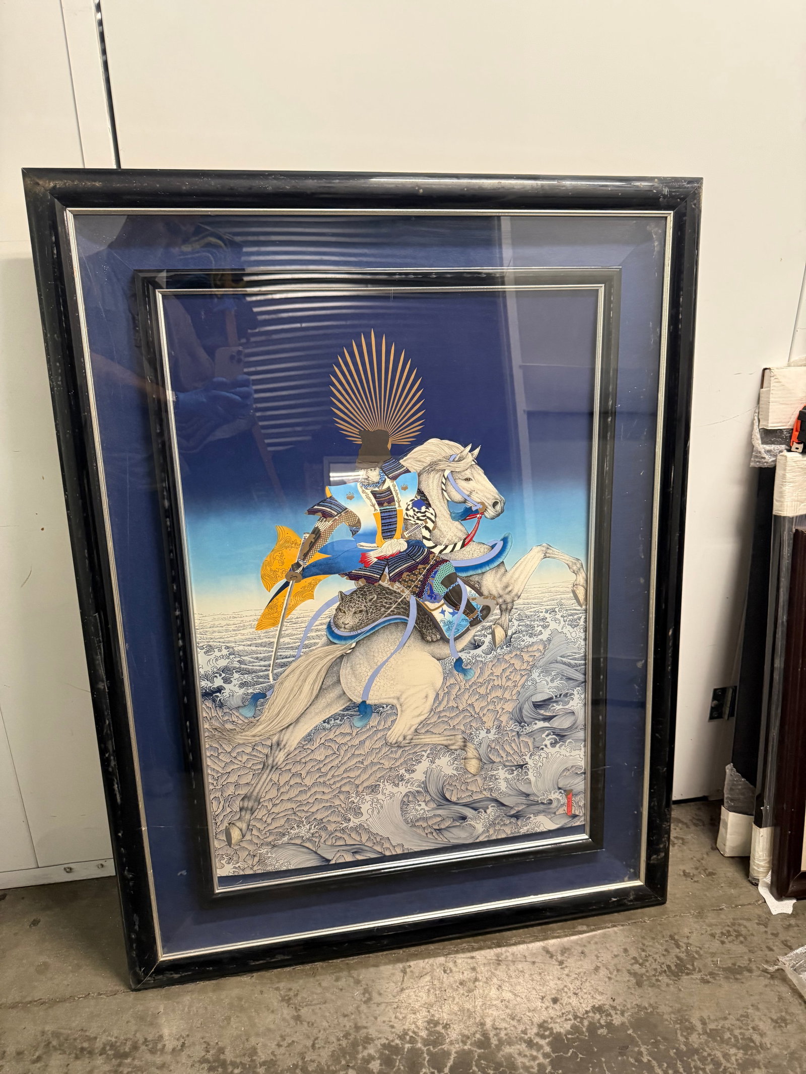 Large Framed Japanese Samurai on Horseback Art Print 50”x37”: Stunning framed art print depicts a samurai warrior in ornate blue and gold armor riding a white horse through crashing waves. This piece has a deep blue background with a golden sunburst motif behind
