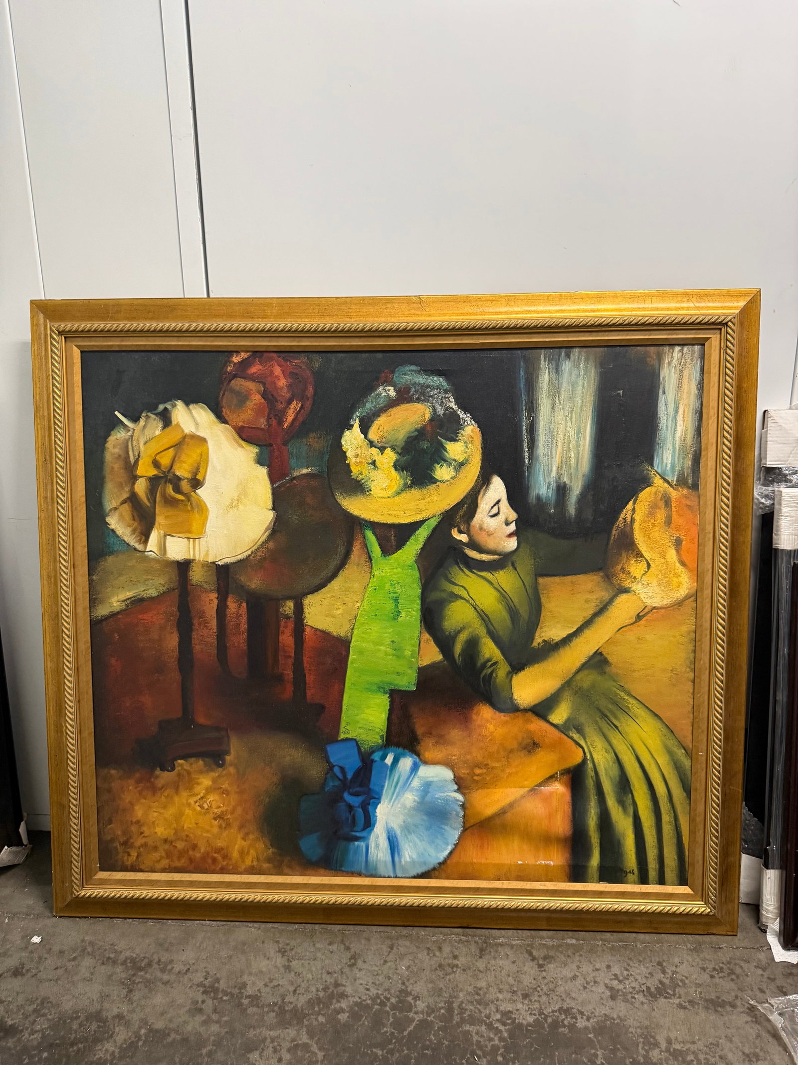 Manner of Degas Oil On Canvas 51”x46”: Large oil on canvas painting depicts a millinery shop scene in the style of Edgar Degas. The artwork is framed in a gold-toned ornate wooden frame. The composition features a woman in a green dress