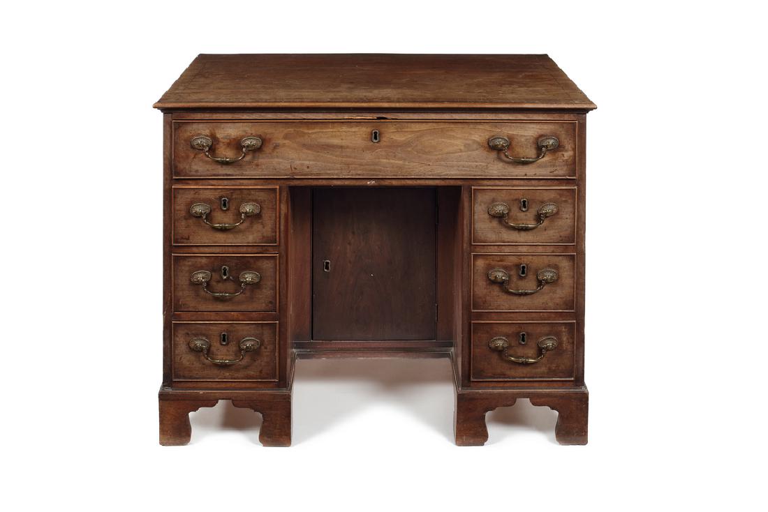 A George II mahogany kneehole dressing table/ desk: A George II mahogany and crossbanded kneehole dressing table/desk in the manner of Thomas Chippendale The rectangular ogee moulded top above a frieze drawer enclosing six short drawers and a corner li