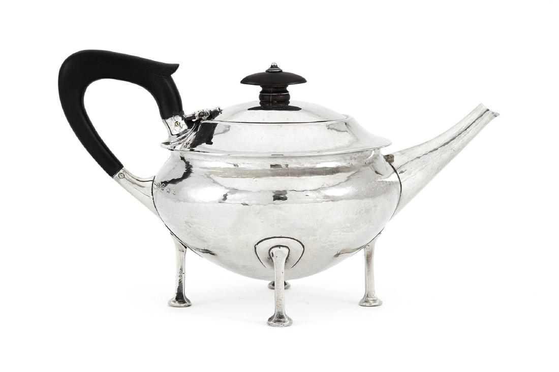 An Arts & Crafts silver teapot by A.E. Jones: A stylish Arts & Crafts silver teapot by A.E. Jones, Birmingham, 1918 Squat circular on four stylised hoof supports issuing from solid horseshoe shaped junctions, lightly hammered surface and angular