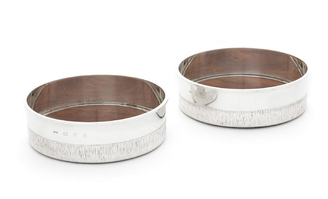 Pair silver wine coasters by Gerald Benney: A good pair of modern silver wine coasters by Gerald Benney, London, 1974 Of good gauge, circular with bark finish band and wood bases, 15.7 cm. diameter.
