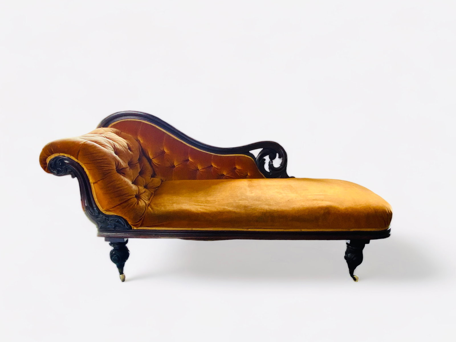A Victorian mahogany carved chaise longue: A Victorian mahogany carved chaise longue The scrolling pierced and moulded buttoned back and arm above a rounded rectangular padded seat, on cabochon carved legs and castors, 180cm wide, 58cm de