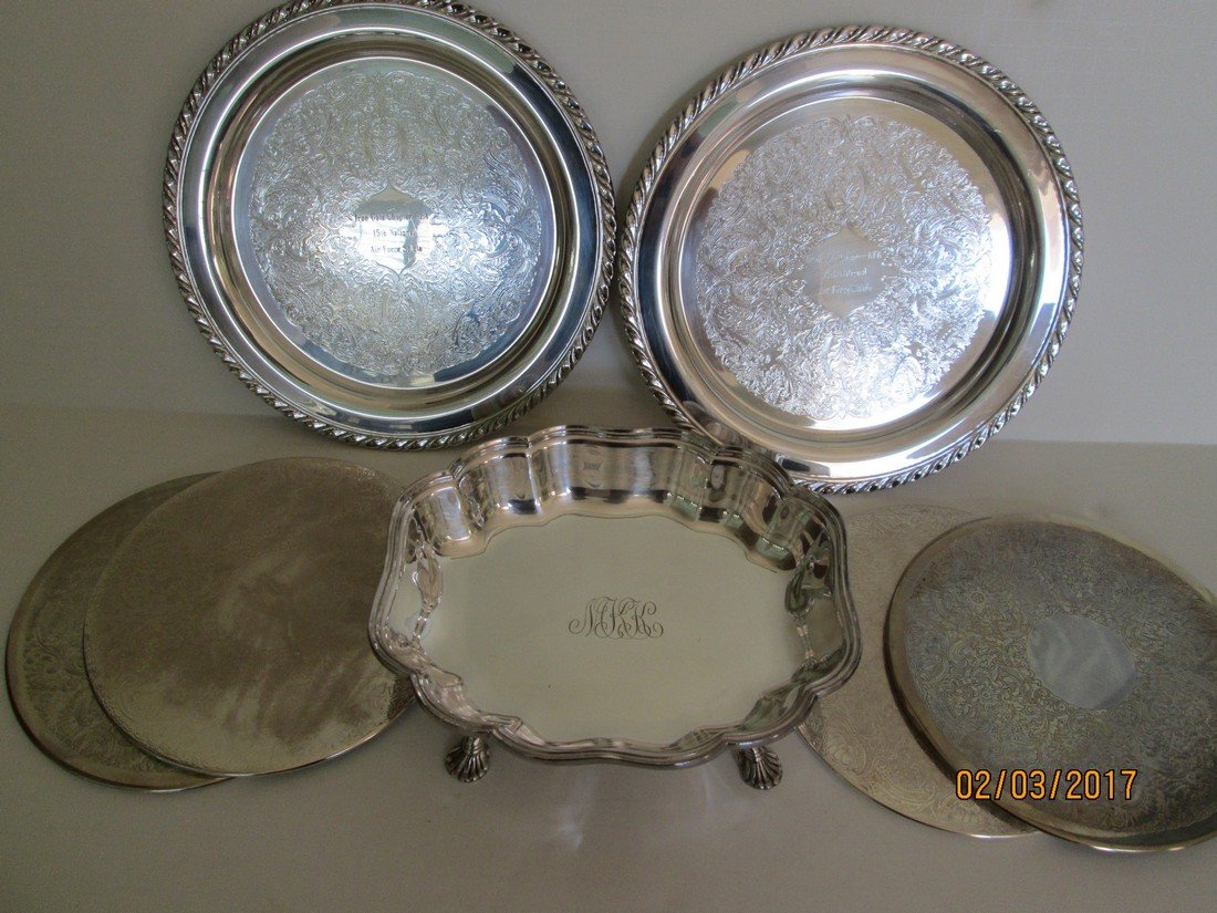 SP servers: Set of four serving trivets (7 7/8”), footed and monogrammed rectangular server (2.5”h x 9”w x 8”d) and two round trophy salvers (10”), all silver plate