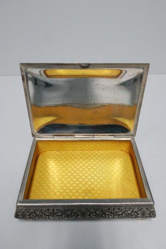 Italian Jewelry Box: A decorative metal jewelry box from Italy. Box is upholstered in a canary yellow. Embossed decorative detail outside; acanthus leaves and Greek key design. Inside interior is upholstered with cushion 