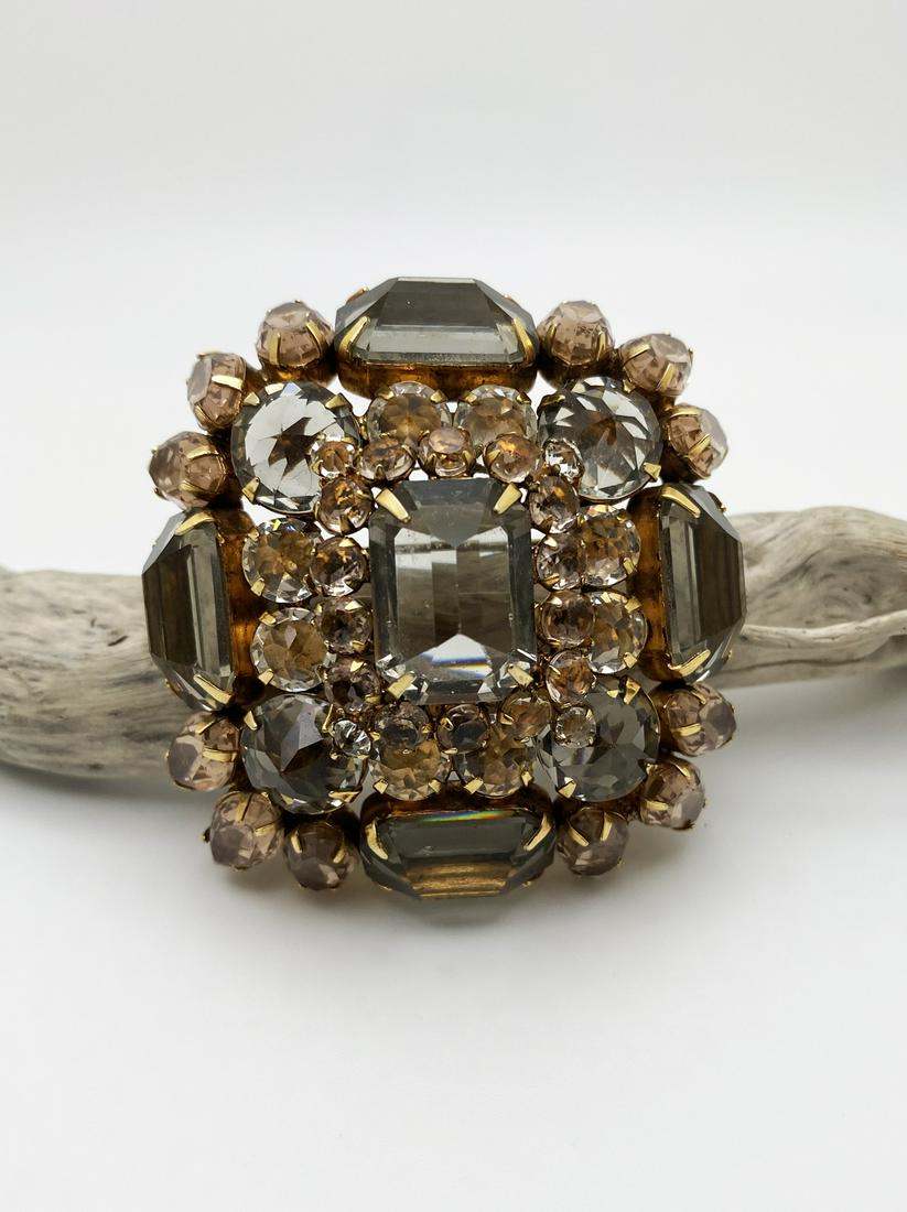 Henry Schreiner Rhinestone Brooch.: Brooch pin shaped as a dome, with a central rectangular smoked faceted glass, settled on an embossed golden metal motif, ornated with 4 matching faceted stones at the edges, and rhinestones in round a