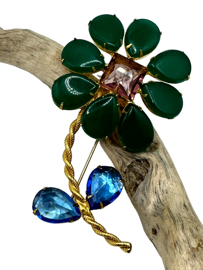 Schreiner green Flower brooch: Flower brooch large green petals cabochon with centered square faceted pick glass, twisted golden tone stem with blue rhinestone leaves. Signed on the back. Full length 4 in.
