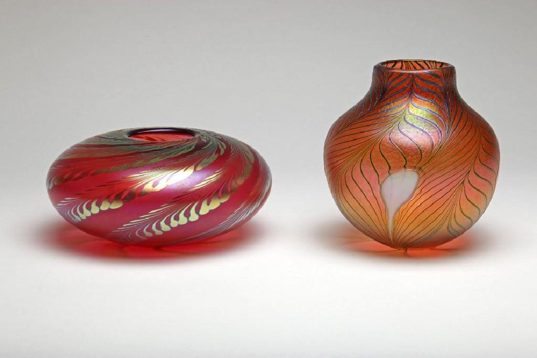 2 Robert Held Iridescent Red Studio Art Glass Canada: Two Robert Held Canadian modern art glass vessels with iridescent pulled feather patterns over red. Etched signature. 1) 4.5 in. H x 9 in. dia. 2)7.5 in. H x 7 in. dia.