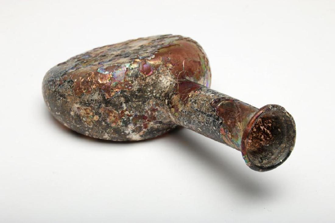 Ancient Roman Glass Longneck Bottle: Star oval ancient glass bottle with iridescent patina, ca 450-500 AD with extreme earth opaque coloration, probably Roman dug. 5.75 in. H x 3.25 in. W.