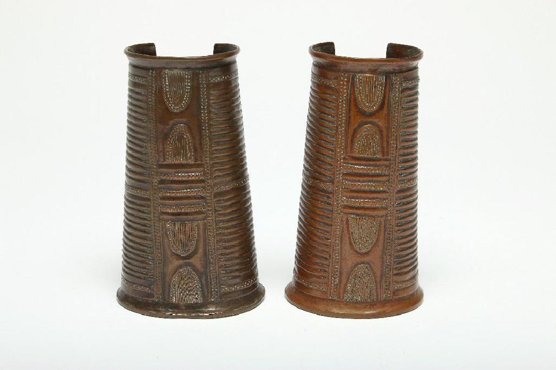 Pair Nigerian Copper Arm Cuffs: Ligbo origin. Approx. measurements:Cuff 1: 6 in long x 3.5 in at widest bottom x 2.5 in widest top.Cuff 2: 5 15/16 in long x 3.25 in widest bottom x 2 in widest top.