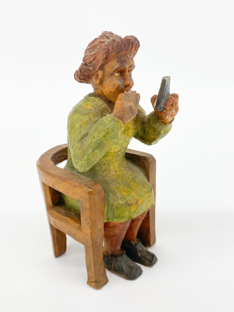 Folk Art Carved Woman on a Chair Putting on Lipstick: Folk Art Carved Woman Sitting on a Chair Putting on Lipstick. Unsigned. Approx. 6 in. x 3 in. x 3 in.