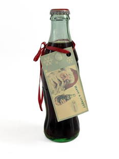 Bill Barminski (b. 1962) Mixed Media Sculpture Crap Cola Bottle: Bill Barminski (b. 1962) Mixed Media Sculpture Crap Cola Bottle. Cola bottle labeled Crap with Santa Claus hang tag with text "Have a crappy X-mas." Signed on hang tag. Some discoloration on cap.