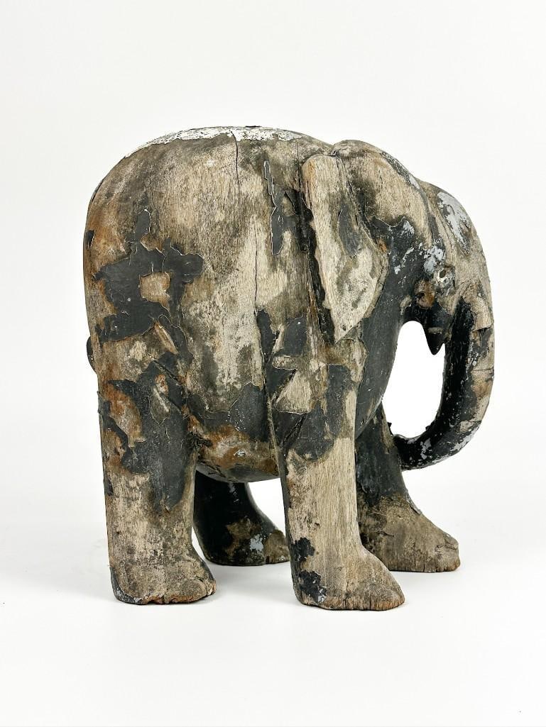 Distressed Folk Art Carved Wood Elephant: This is a well aged elephant carving with patina throughout. It has been stored outside for many years. Condition: One eye missing. Paint loss throughout. Some splitting on wood. Wood is weathered, bu