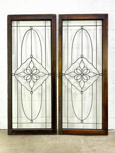 Pair Decorative Leaded Glass Window Panels w/ Floral Design: White paint on one side. Hole along top for hinge mechanism.  Condition: Some minor surface wear.  Dimensions: Each panel measures: 52.5 in H x 21.25 in W x 1.5 in D. Weighs: 49 lbs.