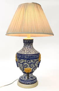 Vintage Ceramic Table Lamp: Vase shaped base has floral motifs and a metal spigot. Glazed ceramic with wooden foot and fabric bouclé lampshade.  Condition: Ceramic has four 1/4 to 1/2 inch chips along a ridge. Chips throughout