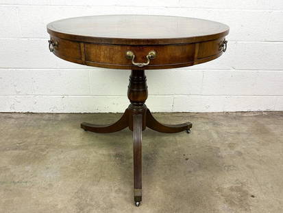Fine Arts Furniture Co Federal Style Round 1940s Leather Top Table w/ 2 Drawers: Three legged. Brass handles and metal capped feet and table is on wheels. Gold accent on edge of leather top.  Condition: Leather top has wear and small circular indentations throughout. One leg has e