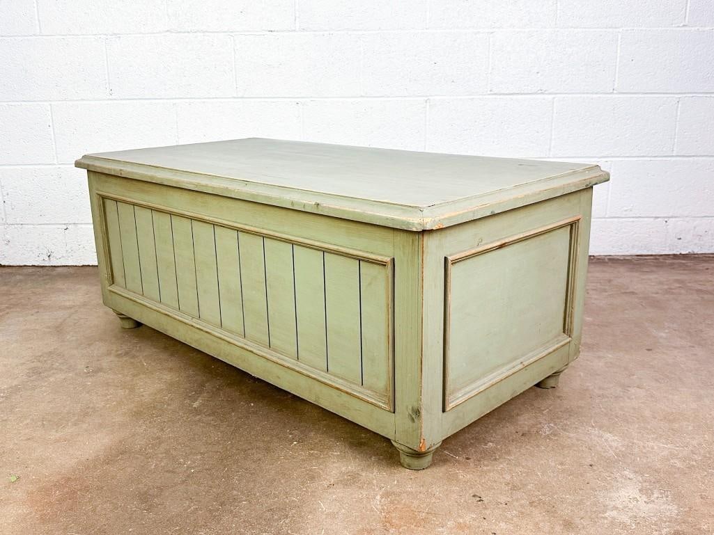 Vintage Wooden Chest: Painted wooden chest opens with hinges and has a flat top. Condition: Good condition. Surface wear throughout. Dimensions: Approximately 17.75 in H x 44 in W x 22.5 in D.