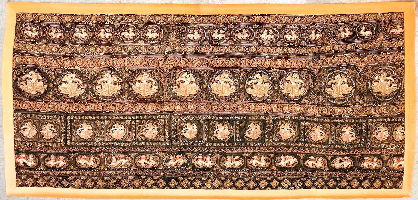 20th Century Burmese Embroidered Tapestry: Antique textile is made of silk applique with embroidered gold, metal sequins, and glass beads. Depicts classic motifs of Burmese textile art. Cotton backing. Approximately 64in H x 131in W. Weighs ap