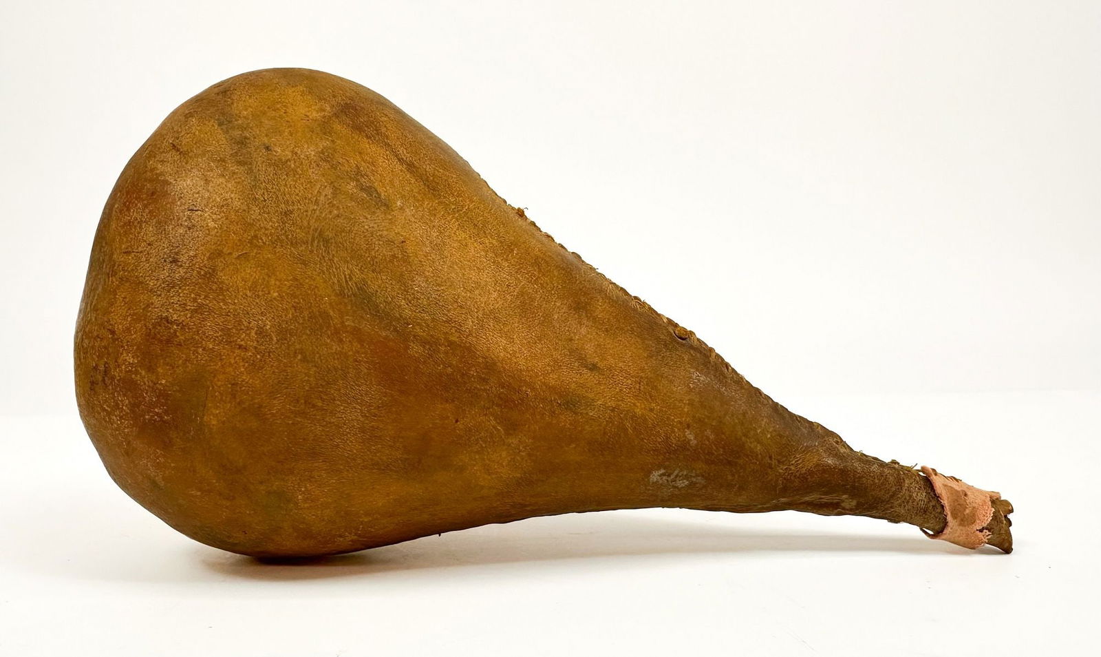 Sioux Rawhide Rattle, Late 19th to Early 20th Century, Great Plains American Indian: Noisemaker is made of sinew sewn rawhide. Handle is missing. Approximately 8 in H x 4.25 in W x 3 in D. Weighs approximately 1 lbs.