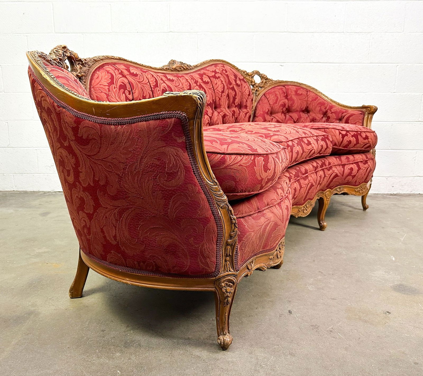 Victorian Style Sofa With Red Damask Upholstery: Carved frame w/ floral design. Red damask fabric.Dimensions: Sofa is approx. 36.5 in H x 79 in W x 33 in D. Seat: 21.5 in H.