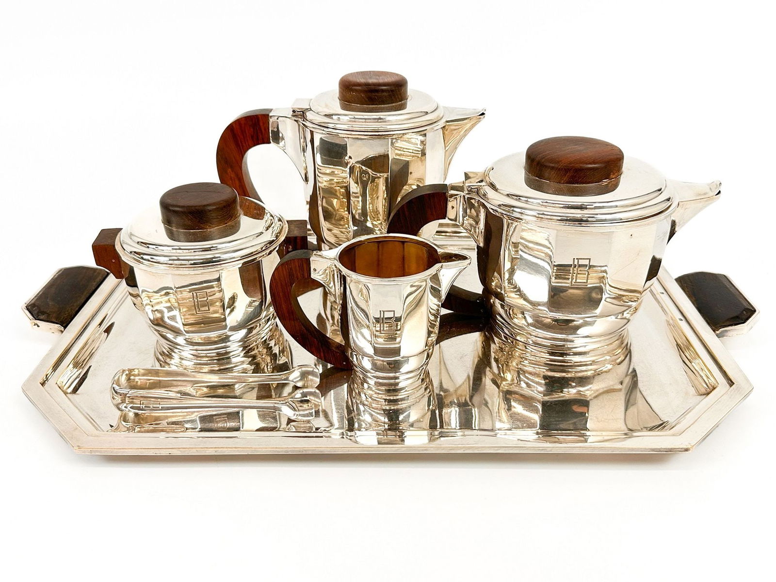 Jean Puiforcat Art Deco Sterling Silver & Rosewood Tea Coffee Service and Silver plated Tray: Service includes one cup, lidded sugar bowl, tongs, tea pot, coffee pot, and serving silver plate tray. Most items monogrammed LB. Tea set made of sterling silver and rosewood. Stamped on the bot