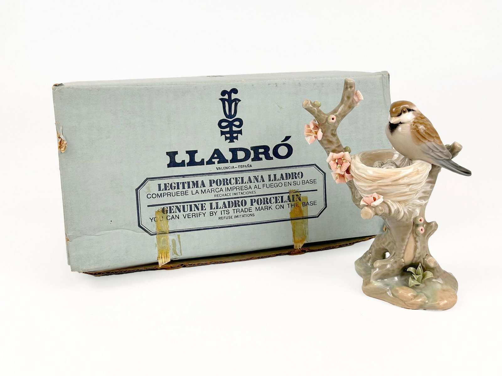 Vintage Lladro Porcelain Figurine Bird in the Nest, 1299 by Vincente Martinez: Titled Bird in the Nest, number 1299. Sculpted by Vincente Martinez. Retired collection piece, issued 1974-1985. Figurine features a brown and white sparrow perched on a flowering branch next to a nes
