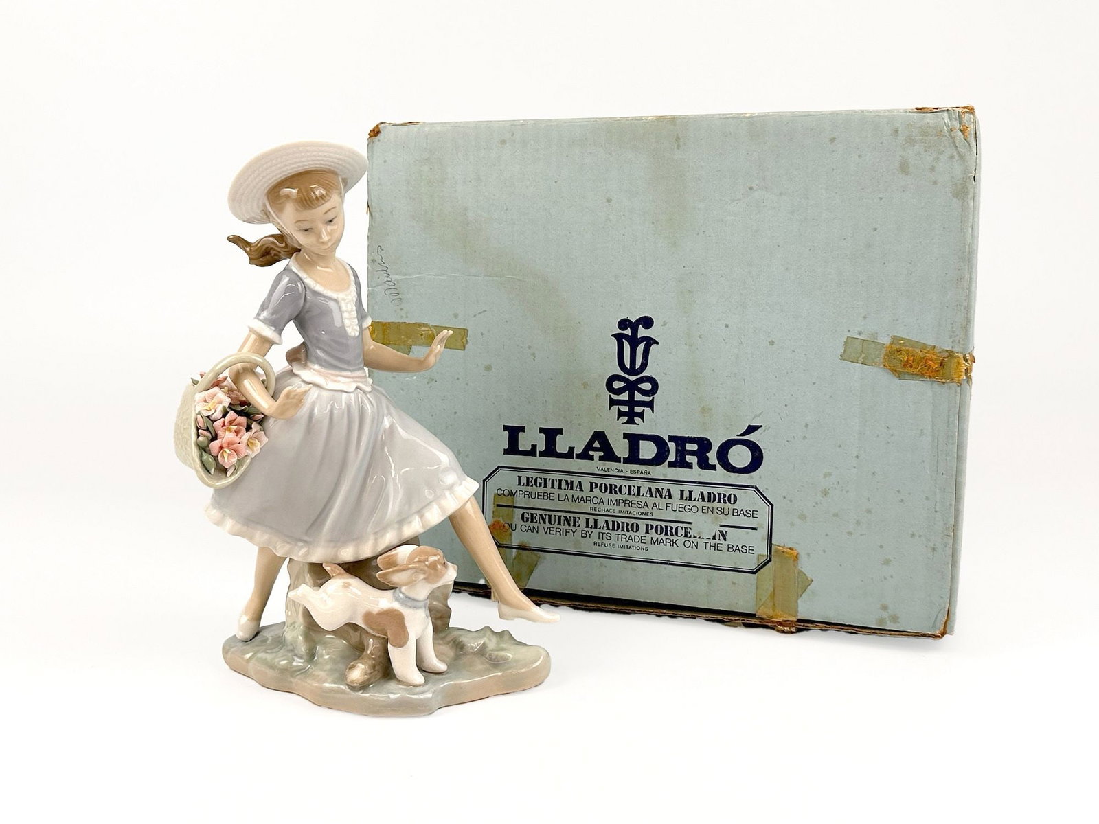Lladro Figurine 4920 Mirth in the Country by Vincente Martinez W/ Original Box: Titled Mirth in the Country, number 4920. Sculpted by Vincente Martinez. Features a young girl in a hat holding a flower basket while accompanied by a puppy. Stamped on the bottom. Comes with original