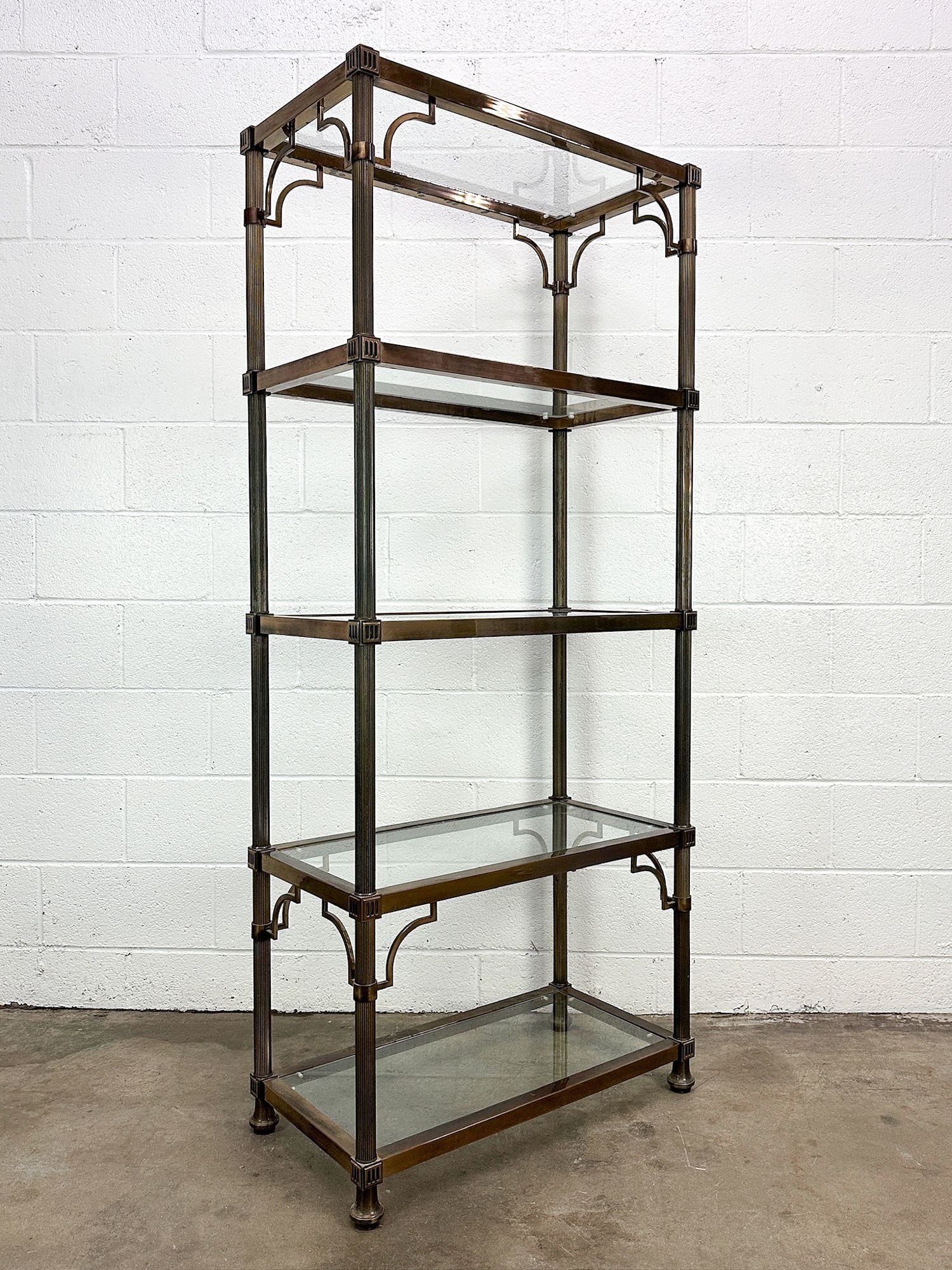 Hollywood Regency Style Etagere Glass Metal Shelf: 5 level glass and metal shelf. Vintage Hollywood Regency metal accents and column motif on frame. Dimensions: Shelf is approx. 70.5 in H x 30 in W x 15 in D.