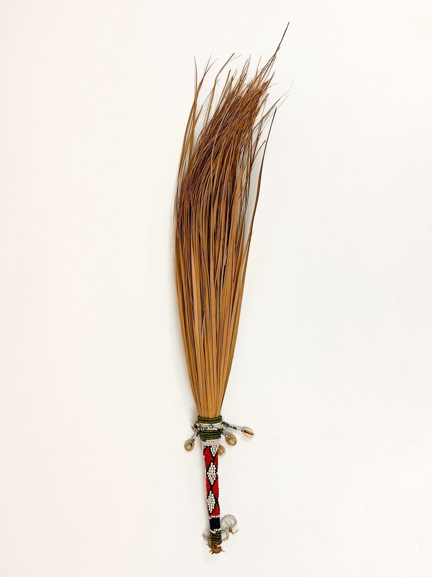 Sioux, Fly Chaser With Cowrie Shells, Mid 20th Century, Great Plains American Indian: Made of dried long blades of grass wrapped together and decorated with glass beads and cowrie shells. Dimensions: Approximately 25 in H x 3 in W x 1.5 in D. Weighs approximately 1 lbs.