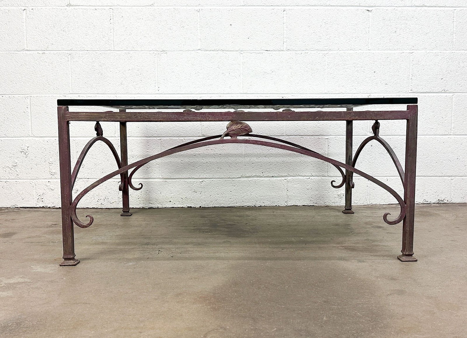 Vintage Wrought Iron & Glass Coffee Table: .75 in thick glass table top. Metal leaf and flower accent in frame. Wrought iron lattice design. Nice patina throughout. Dimensions: Table is approx. 19 in H x 41 in W x 34 in D.