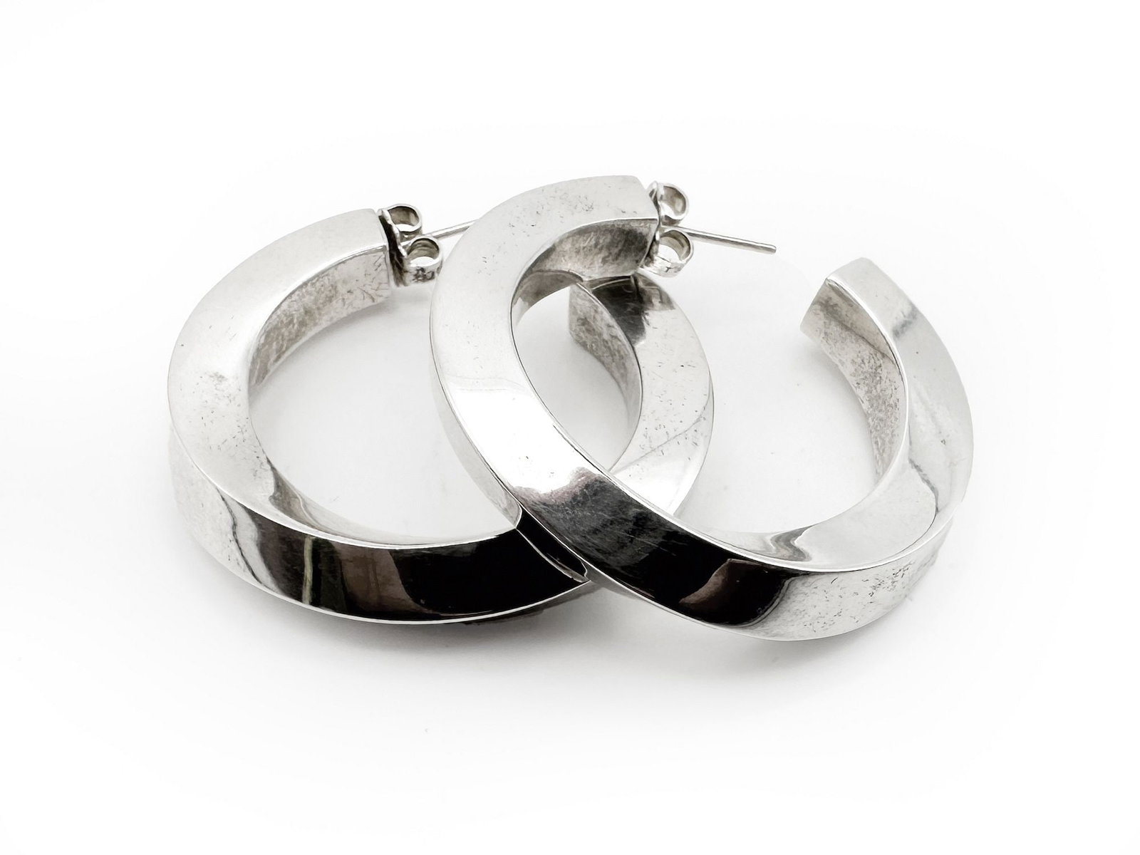 Tiffany & Co. Sterling Silver Twist Hoop Earrings: A pair of Tiffany & Co. sterling silver twist hoop earrings. Each earring measures approximately 1 3/8 inches in diameter and the pair weighs 11.9 grams. The earrings feature a unique twisted desi