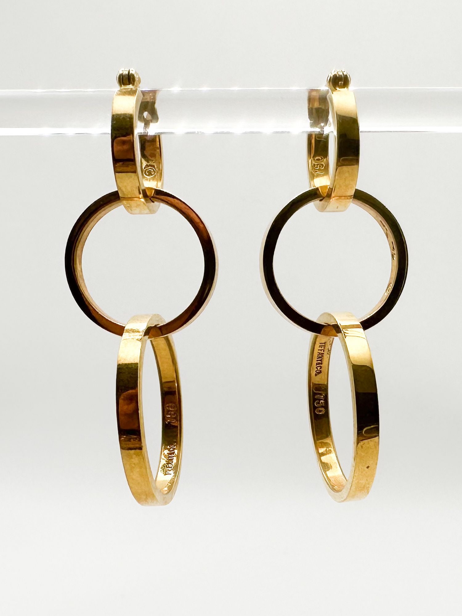 Tiffany & Co. 18K Gold Paloma Picasso 3 Ring Interlocking Hoop Earrings: A pair of elegant Tiffany & Co. 18K yellow gold earrings designed by Paloma Picasso. These interlocking hoop earrings feature a sophisticated design with a total weight of 17.7 grams and a drop of