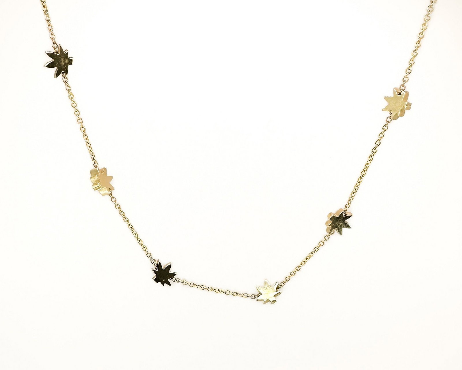 Nova 14K Gold Star/Cannabis Leaf Necklace, Italy: 14K yellow gold necklace by Nova, Italy. The 15-inch chain features starburst or cannabis leaf charms. Weighs 7.7 grams.