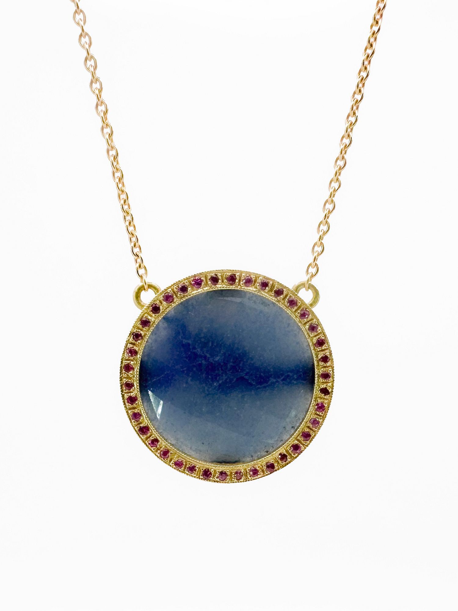 Brooke Gregson 18K Gold Sapphire & Ruby Pendant Necklace: Brooke Gregson 18K yellow gold necklace featuring a faceted opaque sapphire pendant with ruby accents. Chain is 16 inches, pendant diameter is 1 inch. Total weight: 11.8 grams.