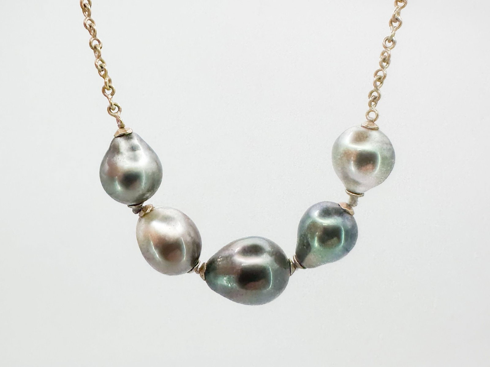 Talisman 14K Gold Tahitian Pearl Necklace: Talisman necklace featuring five Tahitian pearls on a 14K gold infinity chain with a T-bar clasp. Measures 16 inches in length, with the pearls spanning 2 1/2 inches. Weighs 11.3 grams.