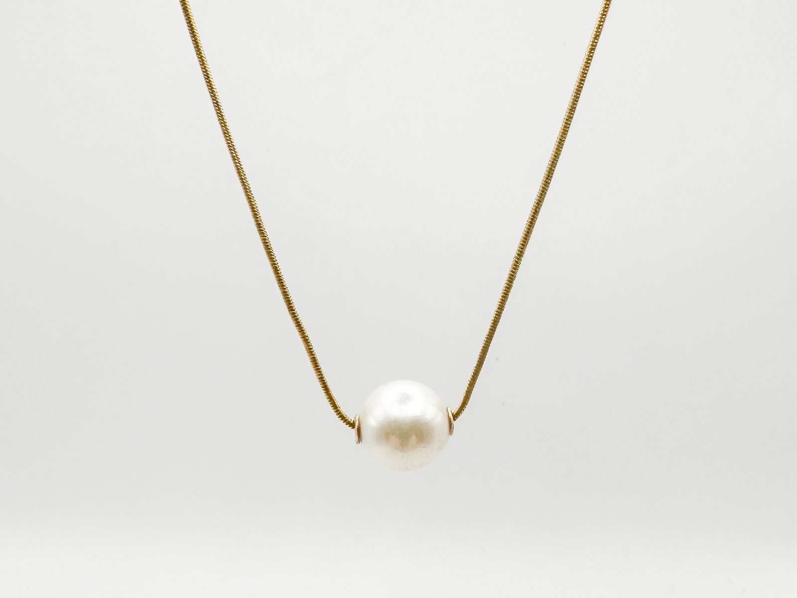 14K Gold and Pearl Pendant Necklace: A delicate 14K gold chain necklace featuring a single, lustrous pearl pendant. The necklace measures 17 inches in length, with a pearl diameter of approximately 1/4 inch. Total weight is 3 grams.