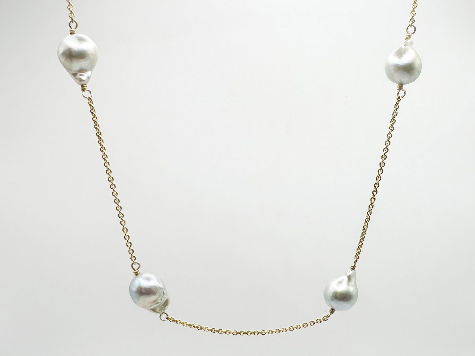 14K Gold Link Chain Necklace with Grey Baroque Pearls: 14K yellow gold necklace featuring a delicate link chain and four grey baroque pearls. Measures 19 inches in length and weighs 9.6 grams.