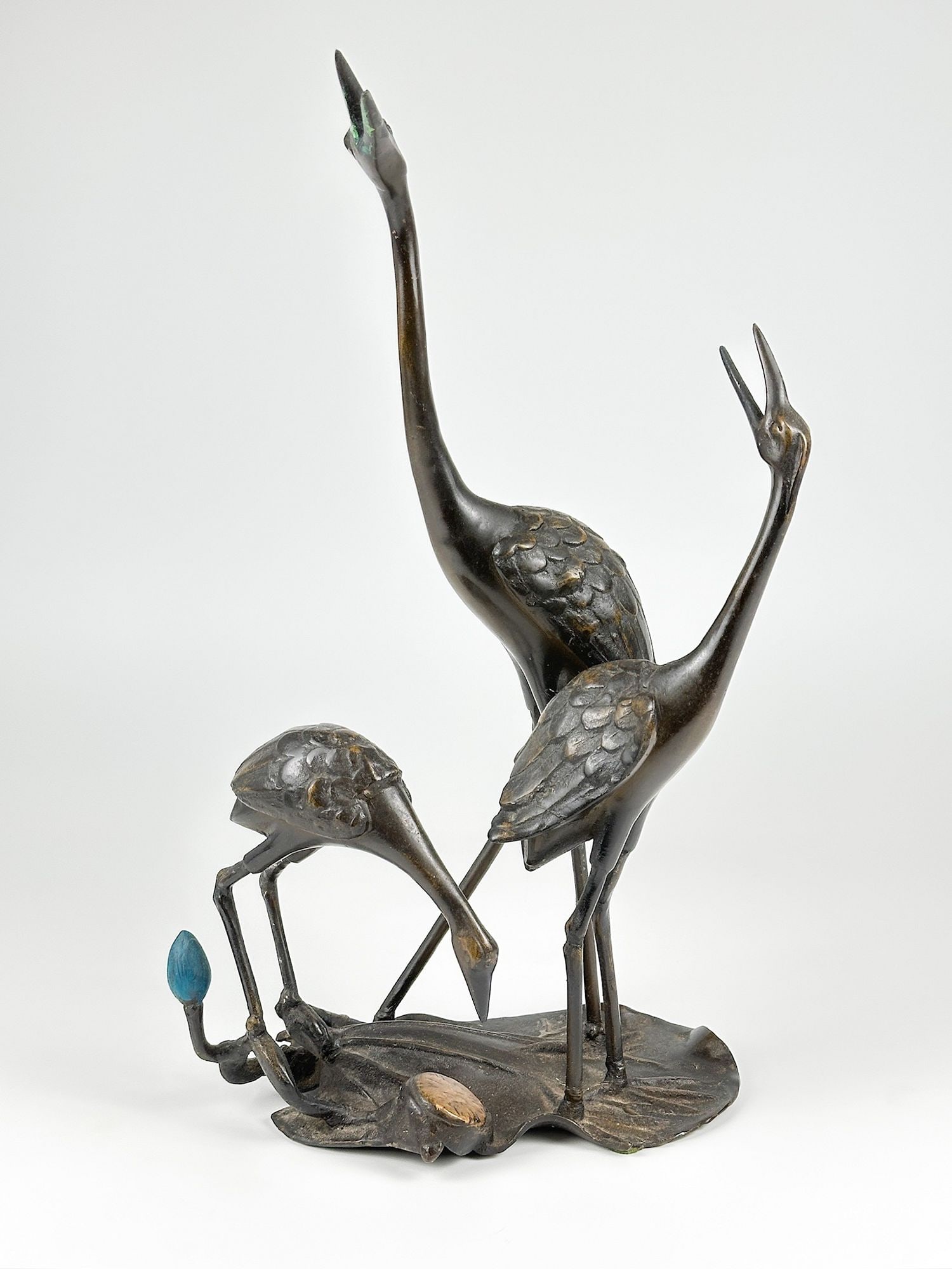 Antique Bronze Okimono of Three Cranes on a Lily Pad: Depicts three cranes on a lily pad, cast in bronze. Various patinas to add color to segments of the work. Named after the Japanese motif of the three cranes. Approximately 18 in H x 10.25 in W x 6 in 