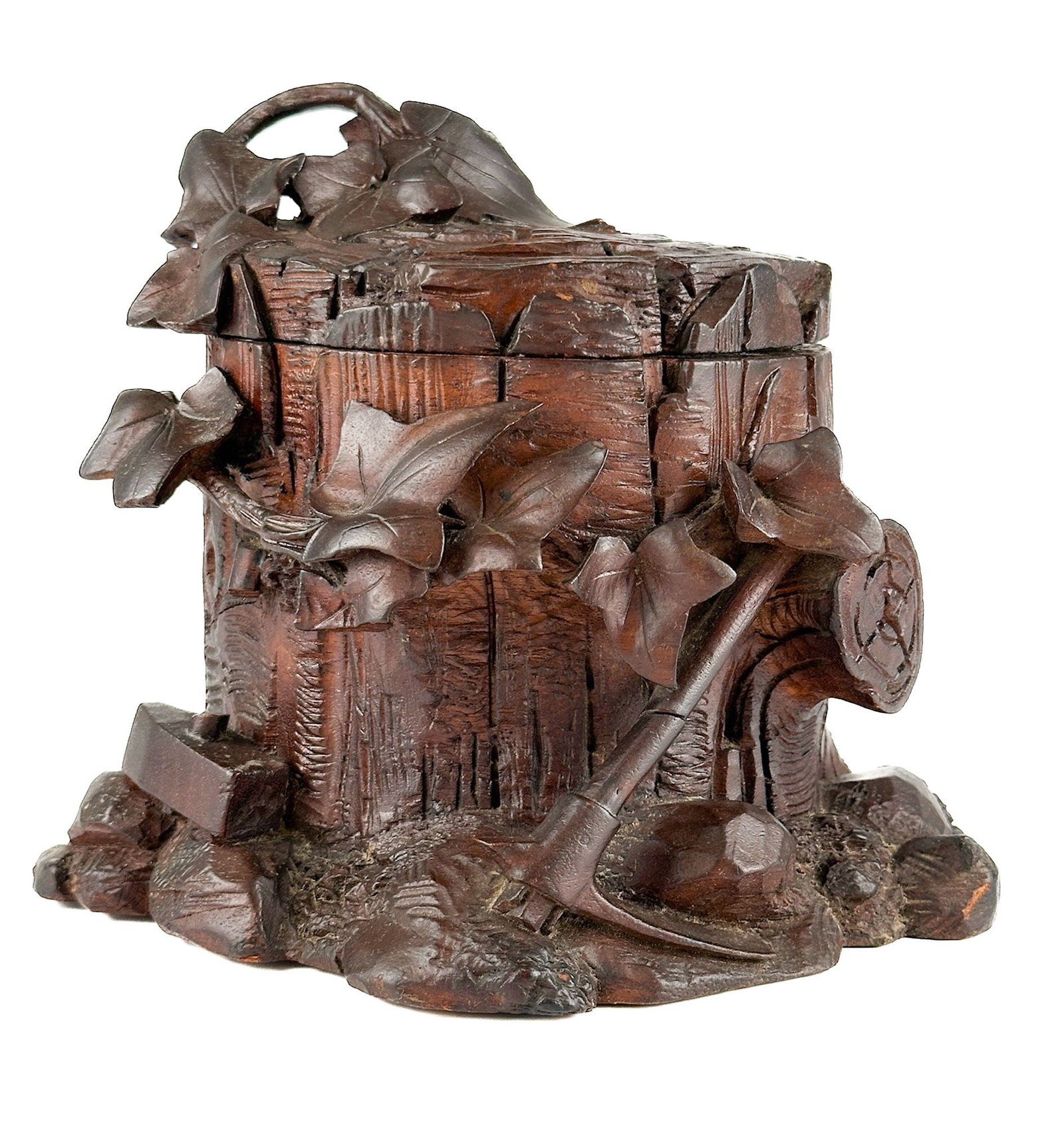 Antique Black Forest Carved Walnut Jewelry Box with Woodcutting Tools Motif: Hand carved in the 19th century. Features detailed renderings of a tree stump and foliage with wood cutting tools. Approximately 7 in H x 9 in W x 7.75 in D. Weighs approximately 1 lbs 13 oz. LOCAL PI