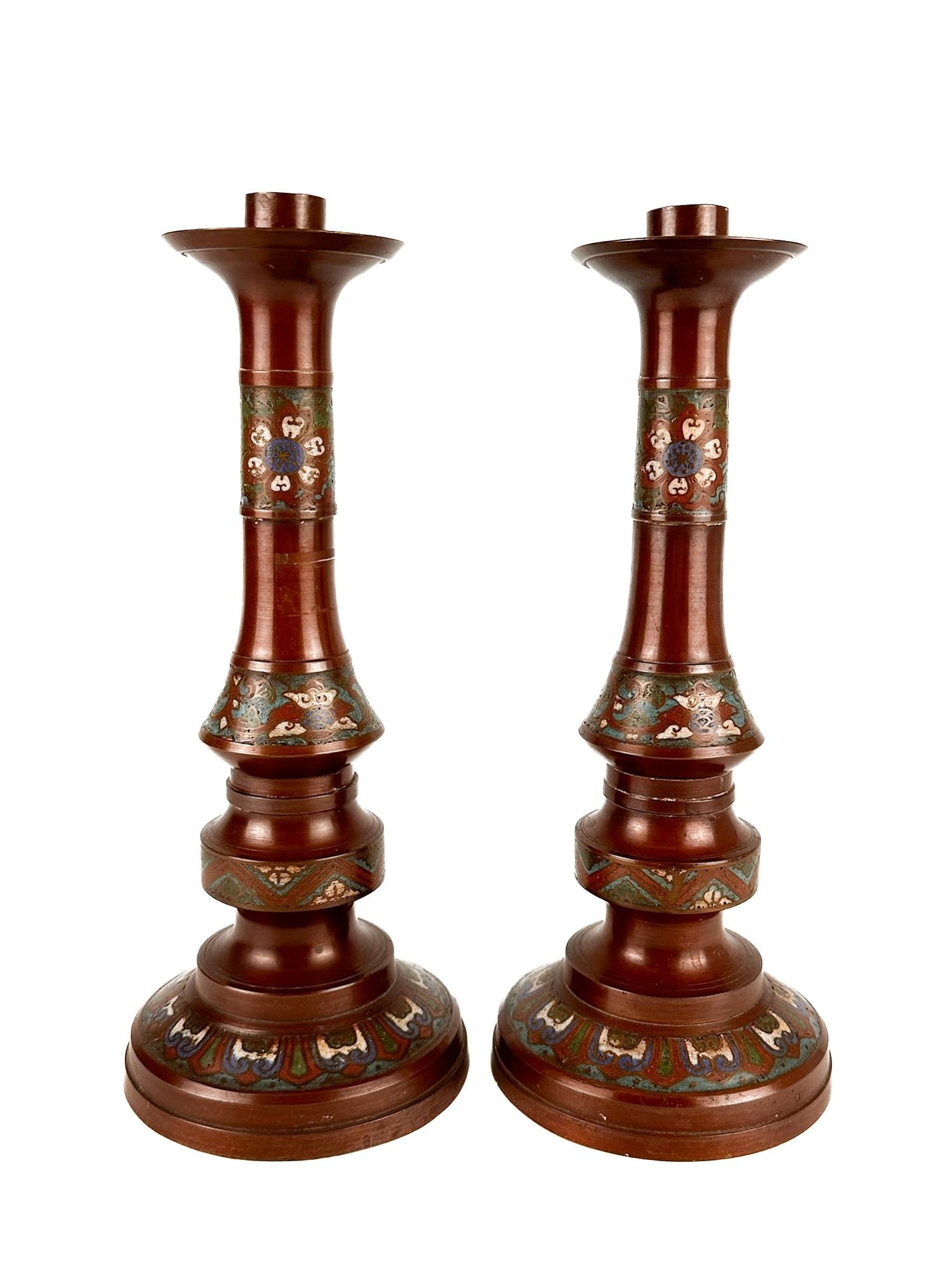 Pair of Asian Bronze Champleve Enamel Candlesticks: Produced in the early 20th century. Painted bronze features decorative enamel inlay with traditional and floral motifs in shades of blue, green, and white. Approximately 12.5 in H x 5 in W x 5 in D.
