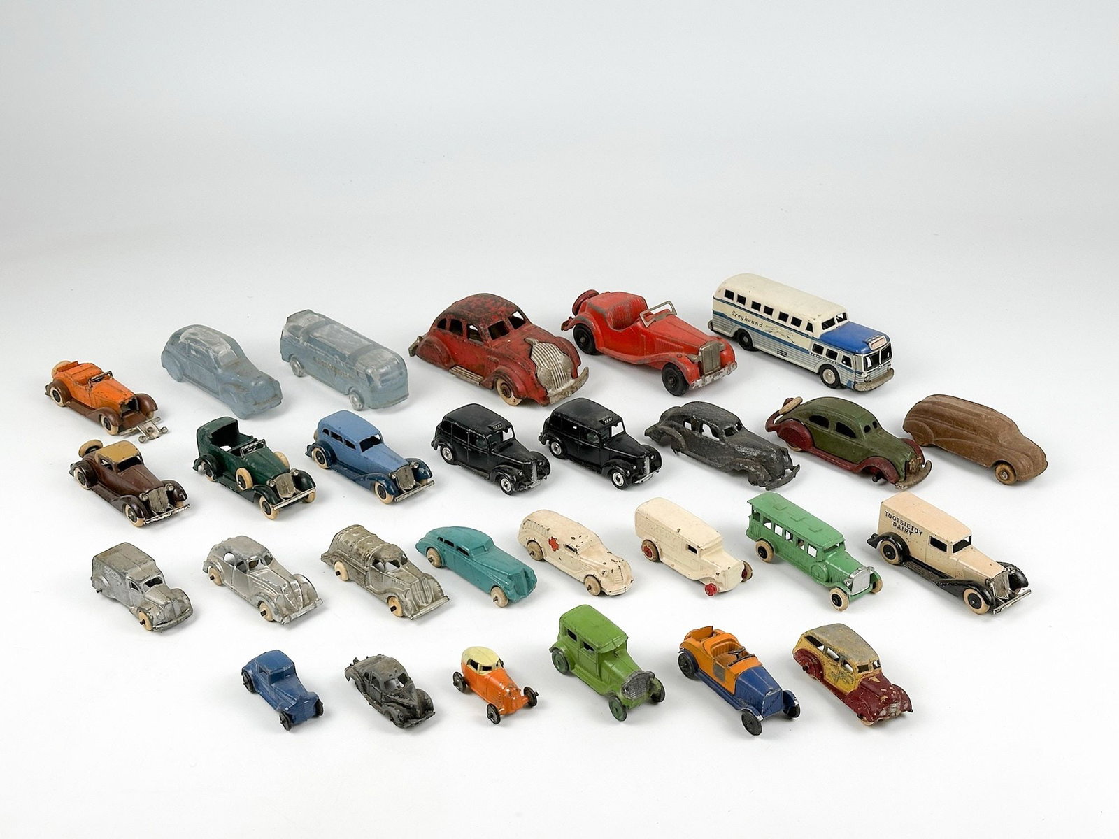 Collection of 28 Vintage Die-Cast Model Cars and Buses: Lot includes cars made of metal or glass with rubber tires. Sizes range from approximately 0.75 in H x 1.25 in W x 2 in D to 2.75 in H x 2.5 in W x 6 in D. Total weight is approximately 5 lbs 8 oz. LO