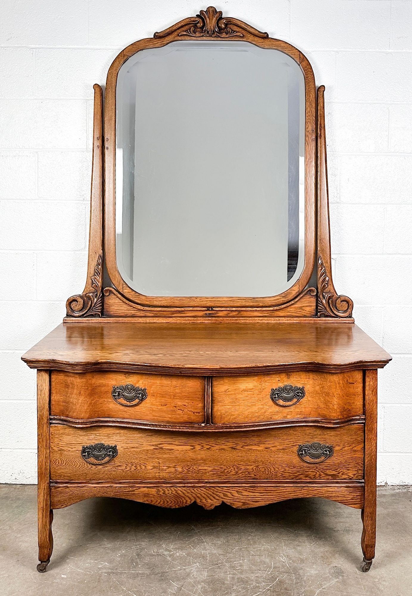 Vintage Oak Vanity Dresser with Swivel Mirror and Carved Details: Carved details along frame of mirror. Cast metal pulls. Casters on legs. Nice oak grain though out. Dimensions: Dresser is approx. 75.5 in H x 45 in W x 22 in D. LOCAL PICK UP INFORMATION: Wednesday, 