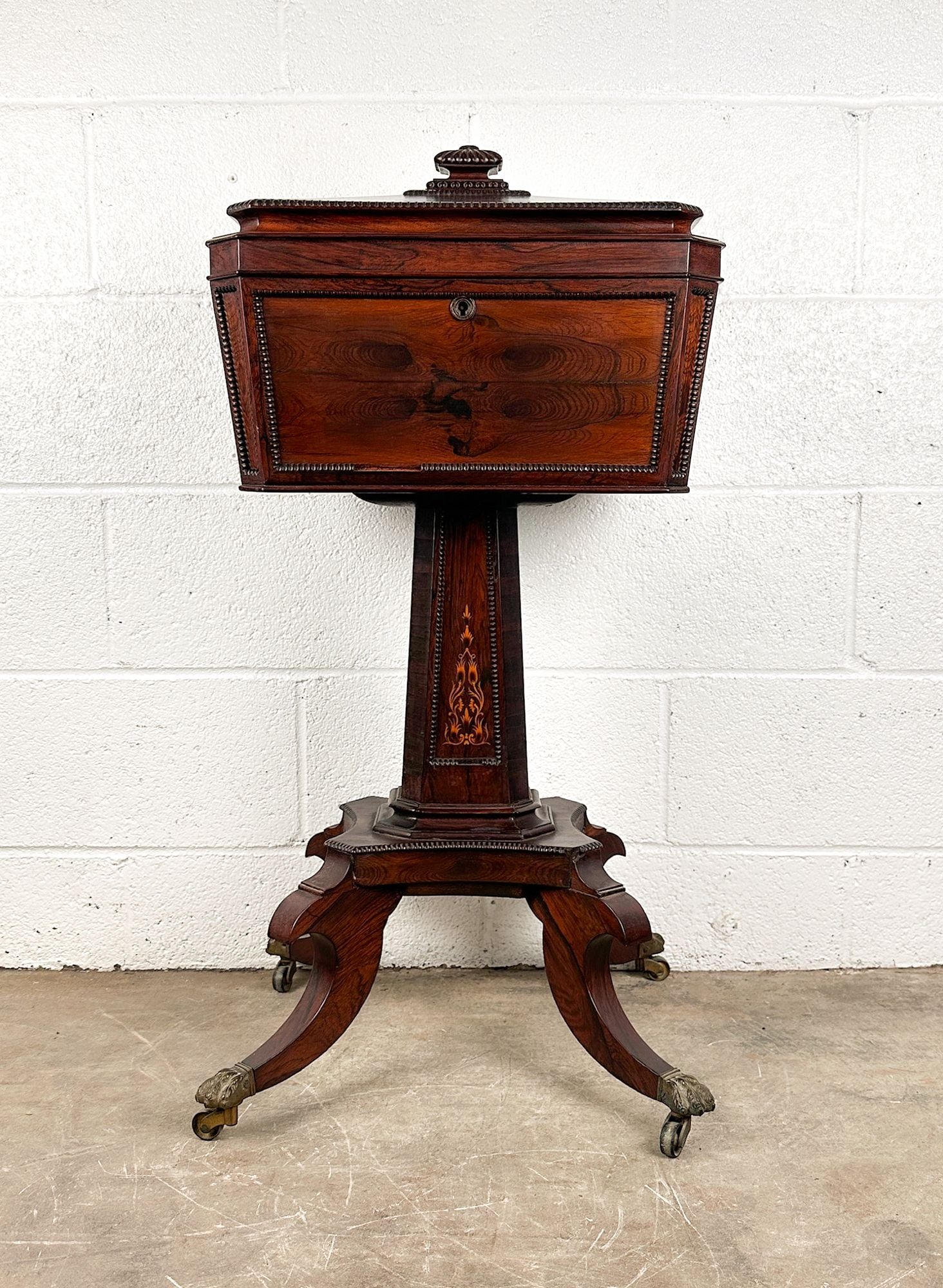 Victorian Regency Teapoy with Inlaid Wood and Clawfoot Hardware: Hinged top. Folded velvet interior lining. Clawfoot hardware. Inlaid wood on base. Two glasses and four hinged compartments for bottles. Dimensions: Teapoy is approx. 33 in H x 16.5 in W x 13 in D. LO