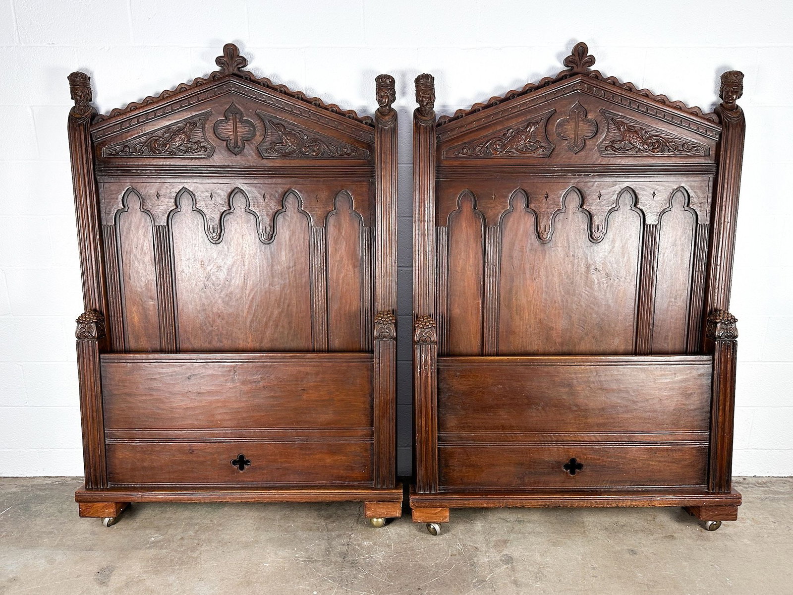 Pair of Antique French Gothic Revival Headboards and Footboards Twin Bedframes: Detailed carvings throughout. Figural finials on headboard. Dimensions: Each headboard is approx. 71 in H x 46.25 in W x 3.25 in D. Each footboard is approx. 34 in H x 48 in W x 3.25 in D. LOCAL PICK 