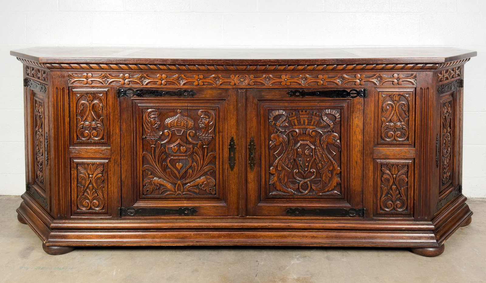 Antique Renaissance Revival Carved Wood Sideboard Console with Keys: Three compartments, each with a single shelf divider. Two drawers. Features intricately carved flora motifs and coat of arms, with hand forged metal work. Includes three keys. Approximately 37 in H x 