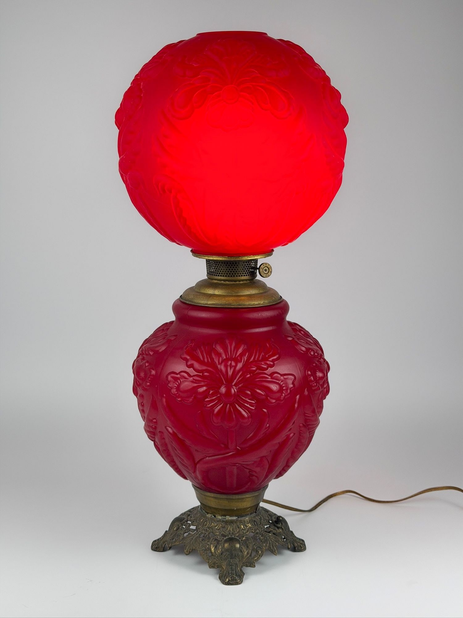 Antique Red Satin Glass Banquet Lamp, Embossed Floral, Rayo Burner: Made of red satin glass with pressed iris flower. Brass base and hardware. Approximately 26.5 in H x 10.5 in W x 10.5 in D. Weighs approximately 10 lbs 5 oz. LOCAL PICK UP INFORMATION: Wednesday, July