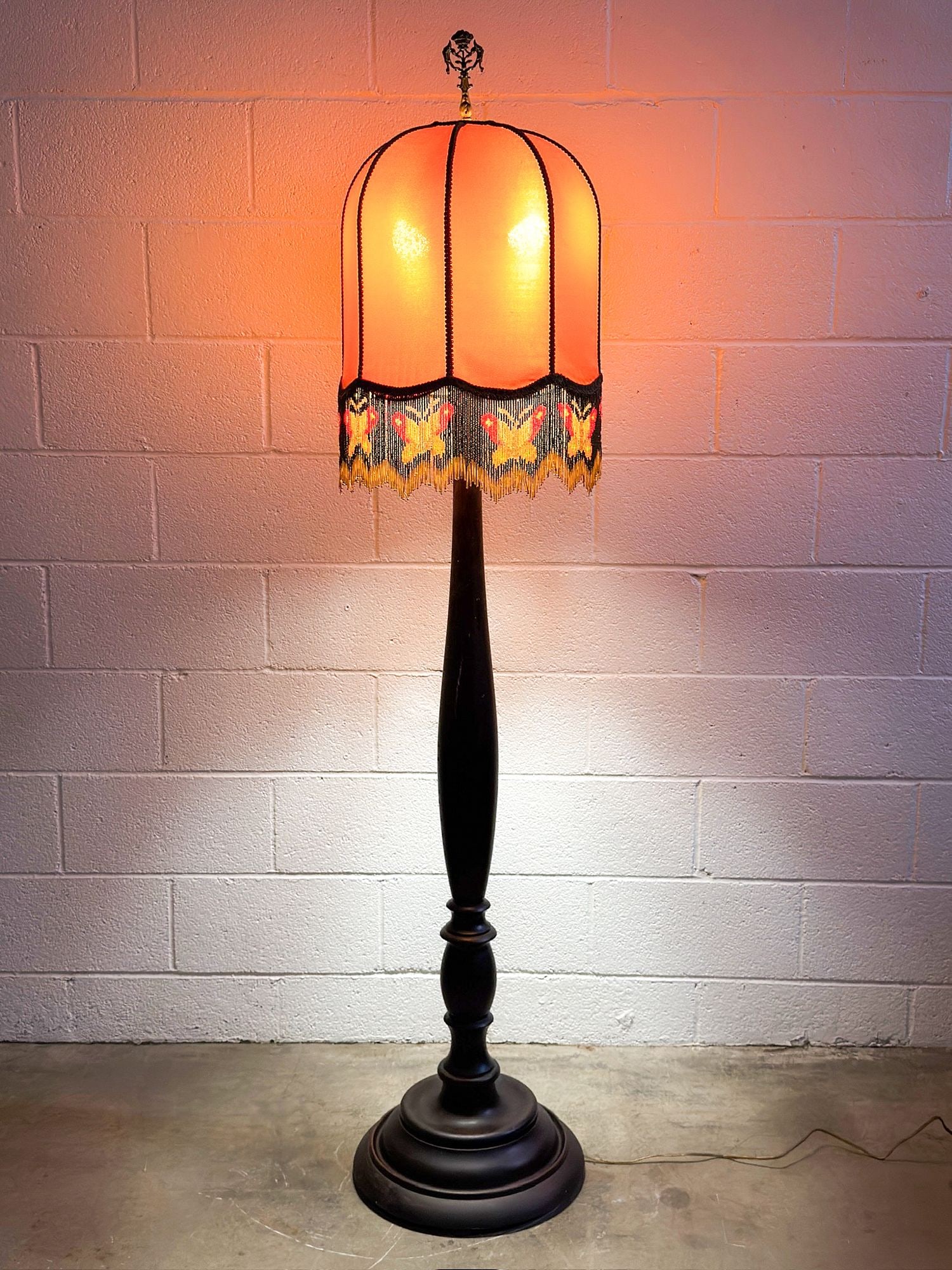 Vintage Turned Wood Floor Lamp with Victorian-Style Beaded-Fringe Dome Shade: Wooden base with fabric lampshade in a warm tan shade. Beaded tassel with butterfly motif. Ornate metal finial. Approximately 71.5 in H x 15 in W x 15 in D. Weighs approximately 21 lbs 9 oz. LOCAL PIC