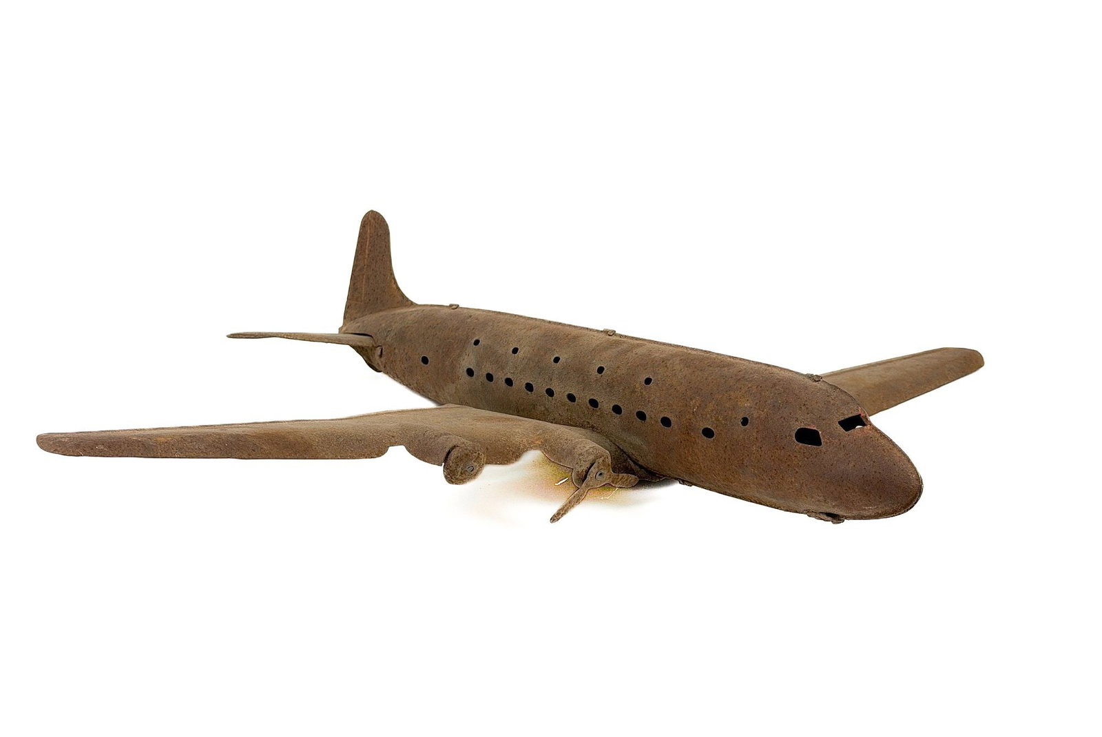 Vintage Folk Art Model of a Four-Engine Airliner Airplane: Four-engine, low-wing propeller airliner circa 1940s-50s. Airplane is constructed of formed metal with cut outs for the windows. Approximately 4.5 in H x 27.25 in W x 21.75 in D. Weighs approximately 